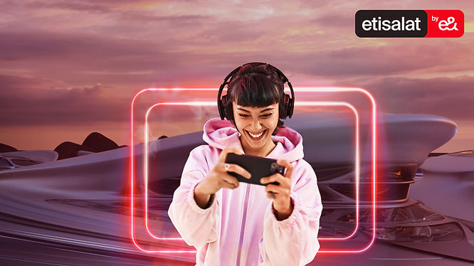 A girl wearing headphone playing on mobile device in front of etisalat e& universe digital twin background.