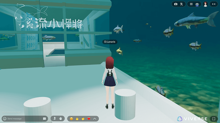 Avatar with red hair stands in an underwater setting with fish swimming by. A structure with text is visible. Interface icons at bottom.