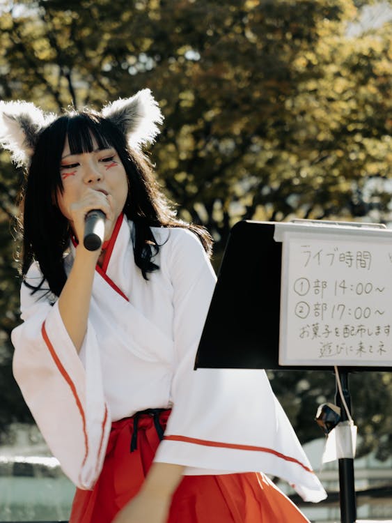 Asian woman in costume performing with a microphone outdoors in Nagoya, representing live idol street performance in Japan