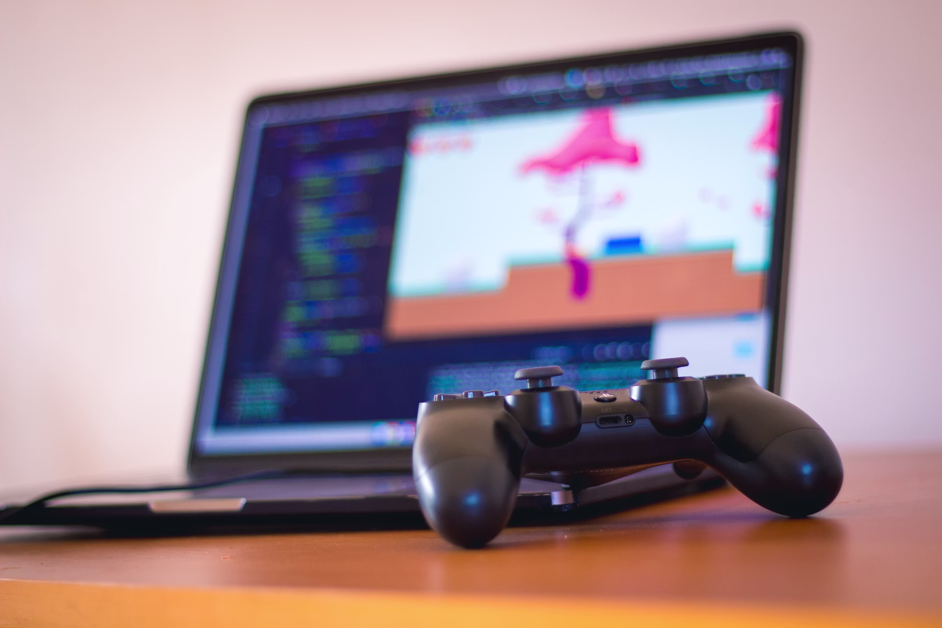 A laptop and a game controller on a wooden desk, the simple setup behind shipping a Godot game to the browser